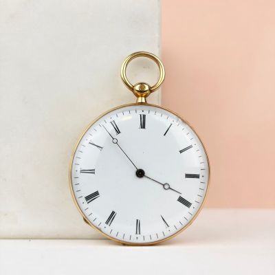 une montre de poche en or posée sur un bloc de marbre
