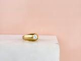 une bague en or sertie d'un diamant repose sur un bloc de marbre