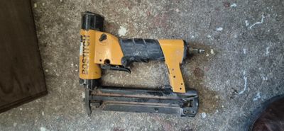un pistolet à clous et une cloueuse posés par terre