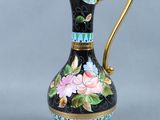 an image of a black and gold vase with flowers painted on it