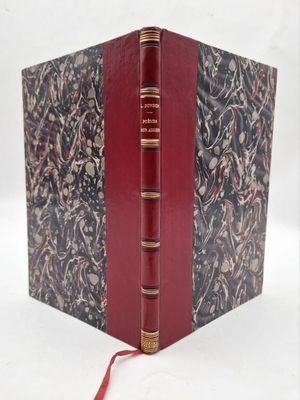 an old book with a red cover sitting on a white surface