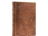 an old book with a brown cover sitting on top of a white surface