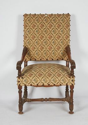 an old chair with a patterned upholstered back and wooden legs
