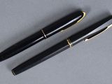 two black pens sitting next to each other on top of a table