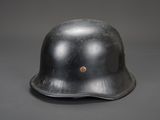 un vieux casque en acier sur fond gris, orné d'un bouton marron