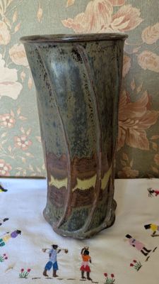 a vase sitting on a table with a floral wallpaper behind it