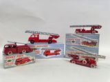 several toy fire trucks are lined up in a row on a white surface