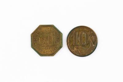 two old coins are sitting side by side on a white surface