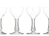 six empty wine glasses lined up in a row on a white surface