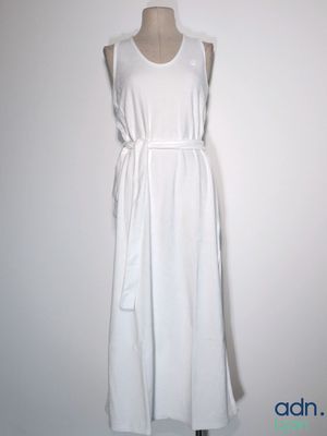 La robe blanche est posée sur un mannequin adossé à un mur blanc.
