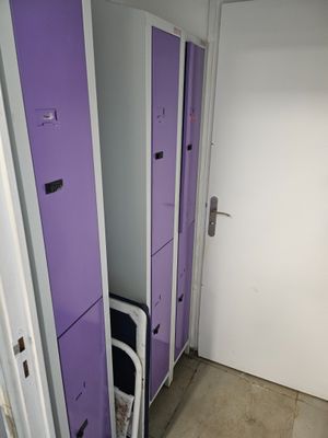purple lockers in a room with a white door and a black chair