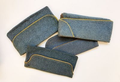 quatre morceaux de denim bleu ornés de coutures jaunes, posés sur un fond blanc