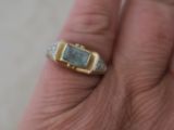 la main d'un homme tenant une bague sertie d'une pierre verte