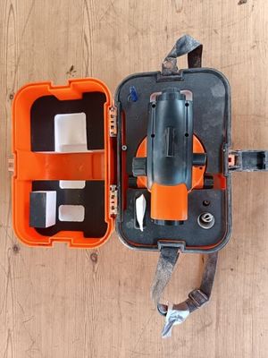 une mallette orange contenant des outils, posée sur un plancher en bois