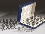des figurines en argent représentant des soldats, dans un écrin bleu sur fond blanc