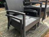 several chairs and a table on a wooden deck in a garden