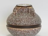 a brown and white vase sitting on a white surface