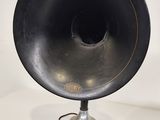 a black speaker sitting on top of a table next to a lamp