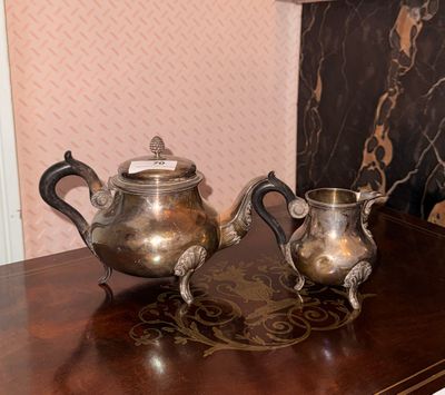 two silver teapots sitting on a table next to a lamp