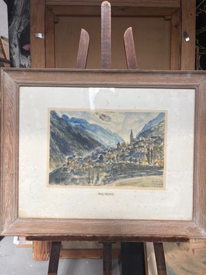 une photo d'un tableau représentant un village de montagne, posé sur un chevalet