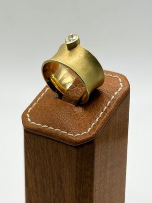 a gold ring with a diamond sitting on top of a wooden block