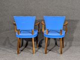 two blue chairs sitting next to each other on a gray surface