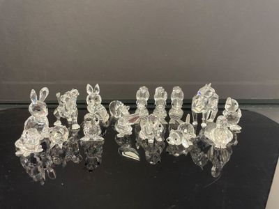 six figurines en cristal posées sur une table noire, sur fond blanc