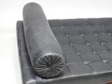 an image of a black leather couch with a rolled up pillow on it