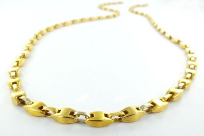 gros plan d'un collier en or sur une surface blanche