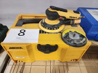 une caisse jaune sur laquelle sont posés une ponceuse et d'autres outils
