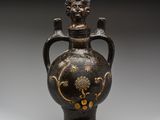 un vase noir et doré orné d'une tête de lion