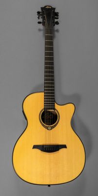 a yellow acoustic guitar on a stand against a gray background