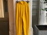 un pantalon jaune accroché au mur à côté d'une plante en pot