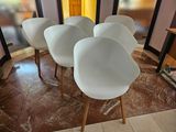 quatre chaises blanches disposées en cercle sur un sol carrelé