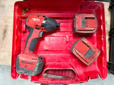 a red tool box with a drill, two batteries, and a charger