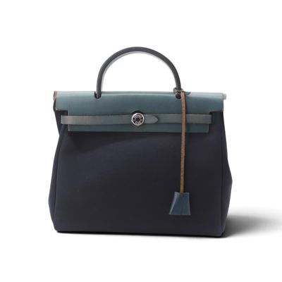 un sac à main noir et bleu dont la poignée est ornée d'un pompon