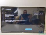 un homme en train de prendre une photo d'un écran de télévision avec son téléphone portable