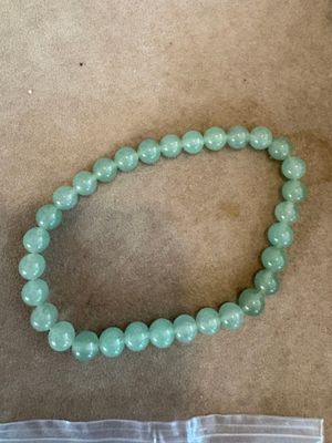 un gros plan d'un bracelet en perles posé sur une table à côté d'un sac
