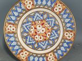 une image représentant une assiette décorative ornée d'un motif bleu et rouge