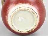 a red vase sitting on a table with a white background