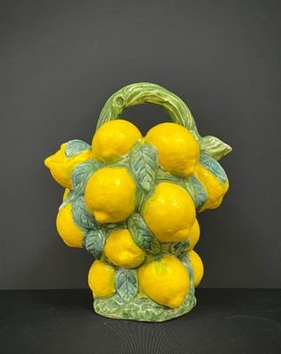 des citrons jaunes dans un panier vert posé sur une table noire