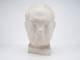 une sculpture blanche représentant la tête d'un homme sur une surface blanche