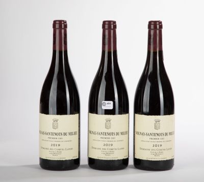trois bouteilles de vin rouge sont alignées sur une surface blanche