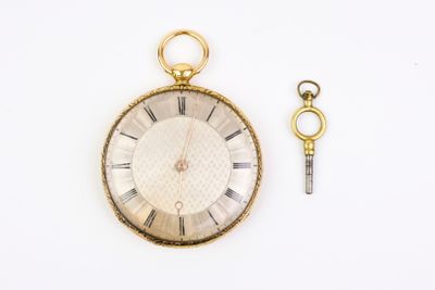 un gros plan d'une montre de poche et d'une clé posées sur une surface blanche
