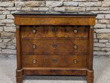 une commode ancienne avec un plateau en marbre, placée devant un mur en pierre