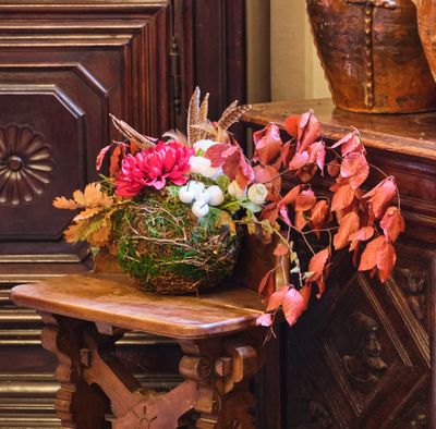 un panier de fleurs posé sur une table devant une commode