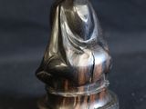 silver figurine of a woman sitting on top of a black surface