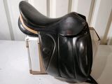 a black saddle on a white table next to a white wall