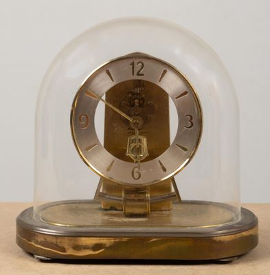 une horloge placée sous un dôme de verre sur une table