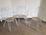 trois chaises en métal blanc placées les unes à côté des autres dans une pièce